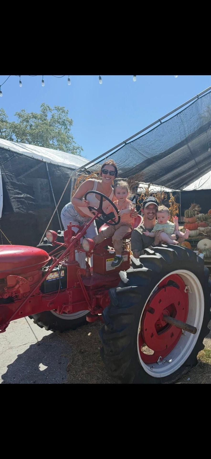 The family with a red tractor on a farm visit